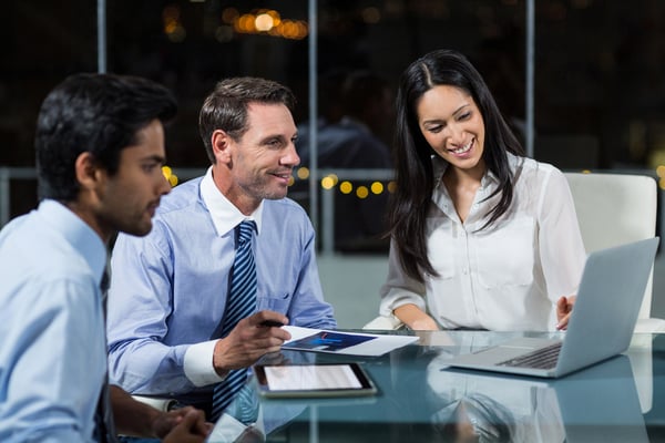 Businesswoman discussing with colleagues over laptop in office