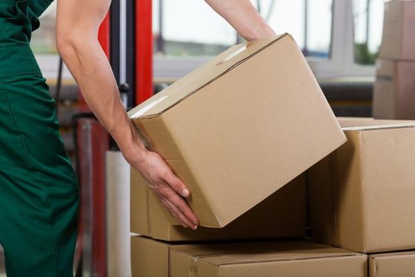 Hands of warehouse worker lifting box, horizontal-1