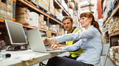 Manager and Warehouse worker looking at laptop PC